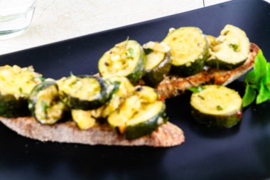 Ekşi ekmek, yükseltilmiş manzara ve manzarayla servis edilen sotelenmiş kabak ya da kabak..