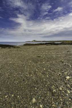 Cemlyn Körfezi 'nin batı ucunda Anglesey, Galler' in kuzey kıyısında. Duvar, çakıl taşı plaj ve deniz, mavi gökyüzü, portre, geniş açı.