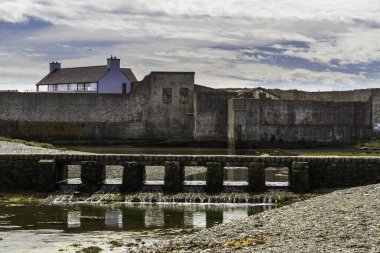Cemlyn Körfezi 'nin batı ucunda Anglesey, Galler' in kuzey kıyısında yaya köprüsü var. Duvar, çakıl taşı plaj ve deniz, mavi bulutlu gökyüzü, manzara.
