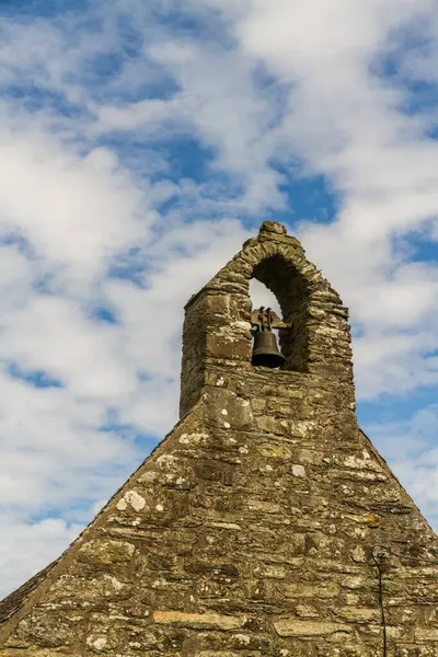 Stock image Small bell tower or belfry of a chapel, stone with blue, cloud streaked sky, portrait