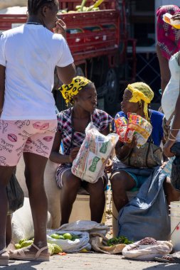Pedernales, Dominik Cumhuriyeti, 22 Ağustos 2022. Sarı bandana şapkalı iki Haitili kadın alışveriş yaparken sohbet ediyorlar..