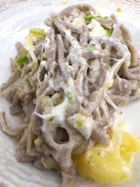 Close up shot of a generous serving of beautiful, tasty, creamy, cheesy pizzoccheri, typical iItalian pasta from the Valtellina region.