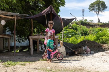Barahona, Dominican Republic, 25 august 2022. Dominican kids, broster and sister, playing with a little pink bike on the edge of the street. Simple caribbean ife.