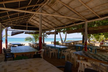 Playa Coson, Dominican Republic, august 2022. View of a typical rustic beach restaurant with plastic chars, palms and amazing sea view.