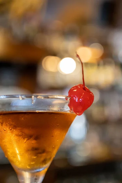 温暖舒适的酒吧内部 非常接近拍摄一个美丽的棕色甜酒或喝马提尼杯 与甜的红色糖果樱桃在玻璃杯的边缘 成年人放松 — 图库照片