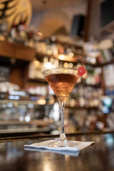 温暖舒适的酒吧内部 近距离拍摄一个美丽的棕色的甜酒或喝马提尼杯 与甜的红色糖果樱桃在玻璃杯的边缘 成年人放松 — 图库照片