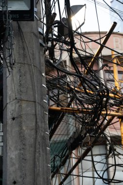 Binondo, Manilas Çin Mahallesi 'ndeki bir direğe bağlanmış kablo ve elektrik kablolarının yakın çekimi. Telefon hatlarında kargaşa ve kaos. Tipik Asyalı metropol görüşü.