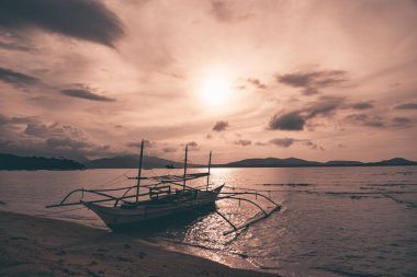 Puerto Prensesi, Palawan, Filipinler. Palawan 'daki bir körfezde balıkçılar tarafından balık tutmak için kullanılan geleneksel Bangka katamaran tekneleri. Neredeyse gün batımı, sihirli ping turuncu ışık.
