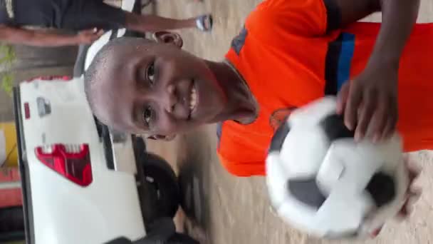 Anse Pitres 2022年8月20日 镜头是快乐的 笑容满面的海蒂安街头小孩儿 穿着鲜艳的橙色欧洲足球T恤 在路中间与足球玩耍 简单的生活 — 图库视频影像