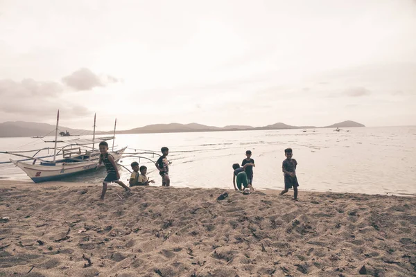 stock image Palawan, Philipines, 28 march 2023. Candid portrait of a group of filipino boys or children playing on the beach running and doing cartwheels. Kids having fun.