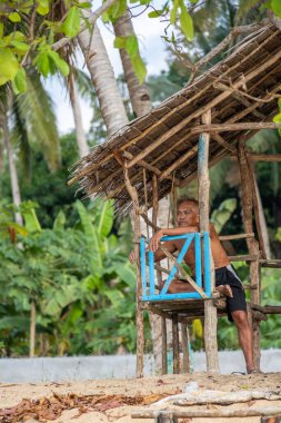 Palawan, Filipinler, 27 Mart 2023. Bir bankın kenarına yaslanmış deniz manzarası, altın ışık, neredeyse gün batımı olan son sınıf bir adamın editör portresi..