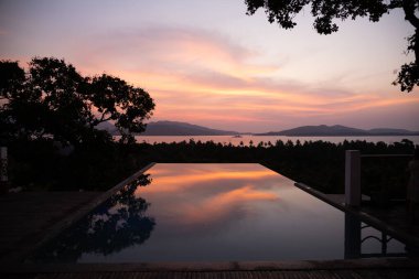 Porto Princesa, Palawan, Filipinler 'de suların üzerinde yoğun turuncu ve pembe gün batımı. Güneş batıyor, gökyüzü yanıyor, altın saat. Gün batımı sonsuz havuza yansıyor. Manzara Görünümü.