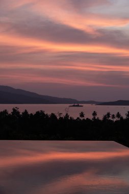 Porto Princesa, Palawan, Filipinler 'de suların üzerinde yoğun turuncu ve pembe gün batımı. Güneş batıyor, gökyüzü yanıyor, altın saat. Gün batımı sonsuz havuza yansıyor. Manzara Görünümü.