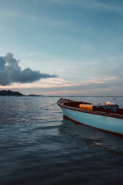 Güneş batıyor ve Seyşeller adası La Digue 'da mavi saat renkleri var. Ön planda yüzen küçük balıkçı teknesi, kopyalama alanı. Rüya gibi bir atmosfer.