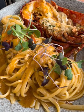 Domatesli ve yarım ıstakozlu deniz ürünleri makarnasının üstünden yakın çekim. Restoran mükemmelliği..