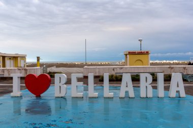 Bellaria Igea Marina, İtalya, 20 Şubat 2024. Plajın önündeki I Love Bellaria şehir heykelinin manzarası. Kış tatili, hiç kimse, sezon dışı, fırtına, dramatik gökyüzü, renk farklılıkları. Kırmızı kalp.