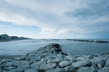 Riviera Romagnola manzarası, kış denizi, kaya resifi, metalik ve dramatik gökyüzü, fırtınalı hava.
