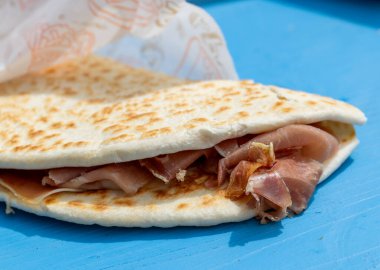 Lezzetli Piadina Romagnola, İtalyan Riviera Romagnola bölgesinden gelen markasız, markasız ama dekore edilmiş yağlı kağıtlara sarılmış, Prosciutto Crudo jambonu ile doldurulmuş otantik sokak yemekleri.. 