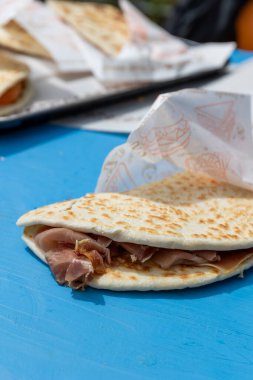 Lezzetli bir Piadina Romagnola, İtalya 'nın Riviera Romagnola bölgesinden tipik bir sokak yiyeceği, açık büfe masasında, Prosciutto Crudo jambonlu. Romagna 'dan otantik yemek..