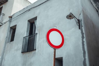 Close up shot of a no access road sign in Sicily, Italy. Color contrast with the walls of an old house in the background.