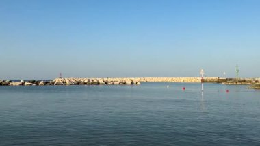 Bellaria Igea Marina limanından gelen kamera koruma kayalarını ve suya yansıyan güzel bir günbatımını gösteriyor. Doğadaki barışçıl güzellik anı. Dikey video.