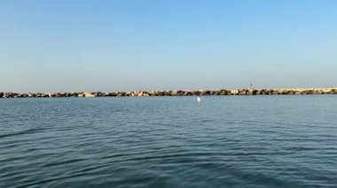 Bellaria Igea Marina limanından gelen kamera koruma kayalarını ve suya yansıyan güzel bir günbatımını gösteriyor. Doğadaki barışçıl güzellik anı.