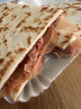Lezzetli bir piadina romagnola yakın çekim İtalyan yassı ekmeği, jambonlu. Riviera Romagnola bölgesinden leziz bir lezzet. Atıştırmalık, yemek, sokak yemeği.
