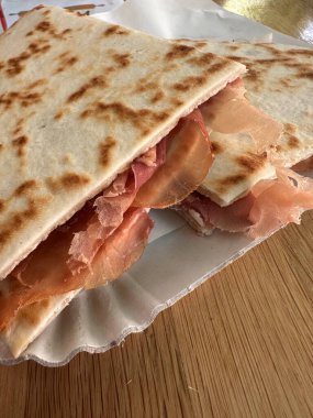 Lezzetli bir piadina romagnola yakın çekim İtalyan yassı ekmeği, jambonlu. Riviera Romagnola bölgesinden leziz bir lezzet. Atıştırmalık, yemek, sokak yemeği.
