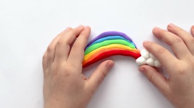 Çocuk bir gökkuşağı ve plastikten bulutlar yontuyor. Çocukların yaratıcılığı