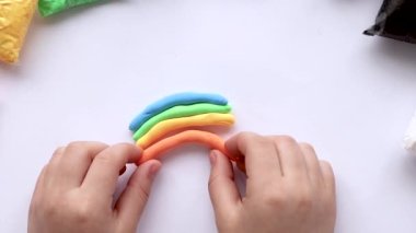 Çocuk heykeller plastikten bir gökkuşağı yapar. Çocukların yaratıcılığı