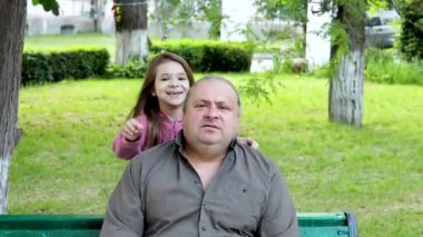 Parkta babasına sarılan küçük bir kızın yakın çekimi. Mutlu baba-kız kavramı. Babalar Günü. Yavaş çekim videosu.
