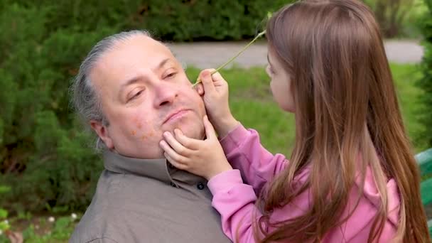 소녀는 공원에 할아버지와 할아버지의 얼굴에 다발을 가지고 그림을 그립니다 여행을 — 비디오