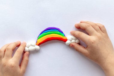 Çocuk bir gökkuşağı ve plastikten bulutlar yontuyor. Çocukların yaratıcılığı
