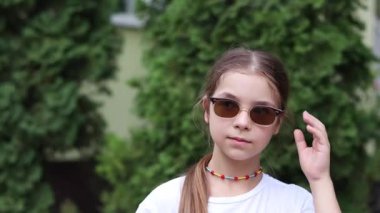 Modaya uygun küçük kız güneş gözlüğünü çıkarıp etrafa bakıyor.