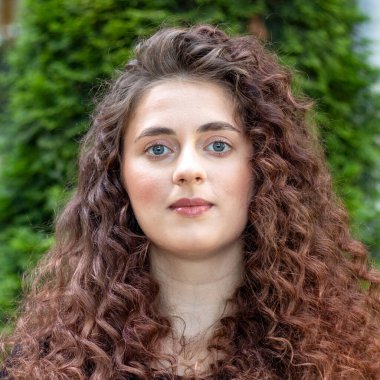 Uzun kıvırcık saçlı esmer bir kadının yakın plan portresi. Dalgalı saç stili olan güzel model kadın.