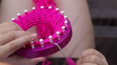 Çocuk dokuma tezgahıyla sarı iplik örüyor.