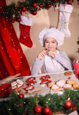 Noel dekorasyonu ve Noel atmosferiyle çevrili kurabiye pişiren genç bir kız.