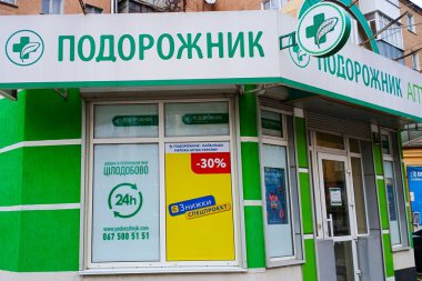 Yeşil aksanlı eczane vitrinleri ve 24 saat hizmet tabelaları sergileniyor.