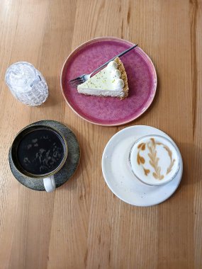 Kahve ile servis edilen bir tatlı dilimi ve yaratıcı bir şekilde latte sanat tasarımı sunumu.