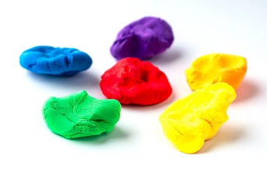 Beyaz üzerinde çeşitli canlı renkler gösteren çok renkli kil modelleme parçalarının yakın çekimi