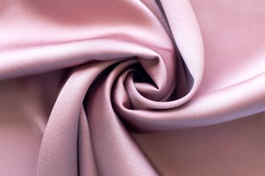 Zarif kıvrımları ve lüks dokusu olan pembe parlak kumaşın soyut makro görüntüsü