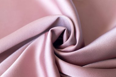 Ayrıntılı kıvrımları ve lüks dokusunu gösteren pembe saten kumaş yakın plan.