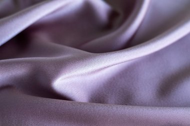 Estetik yumuşaklığı ve akış kıvrımlarını vurgulayan pürüzsüz dokusu olan zarif leylak kumaş.