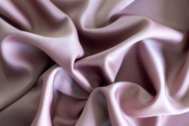 Yumuşak ışık altında pürüzsüz dokuyu ve hassas kıvrımları gösteren pembe kumaş