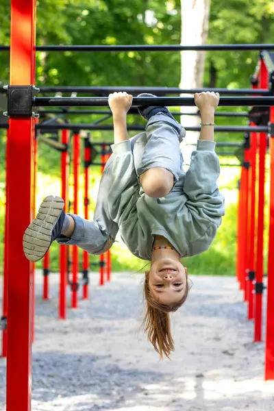 Yeşil ağaçlarla çevrili açık hava barlarında baş aşağı oynayan kız