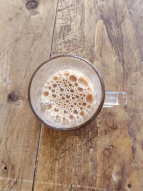 Tahta bir masanın üzerinde bir bardakta kahve. Üst görünüm