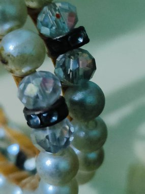 Yeşil arkaplanda incilerden bir bilezik kapat.