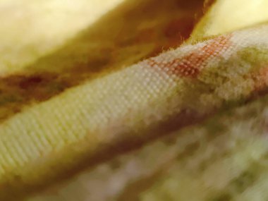 Bulanık arkaplanı olan sarı ve kahverengi bir kumaşın makro fotoğrafçılığı