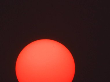 Kırmızı güneş siyah camın arkasında.