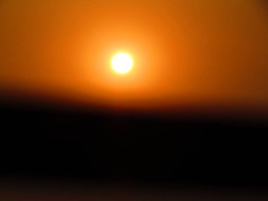 Bulanık güneş ve gün batımı, koyu turuncu bir gökyüzünün arka planında. Şehirde güzel bir gün batımı.